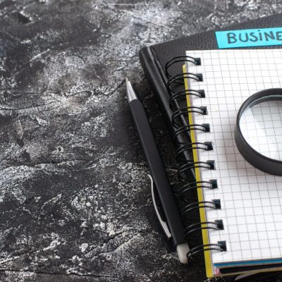 front-view-business-note-with-notepads-magnifier-dark-background-scaled.jpg